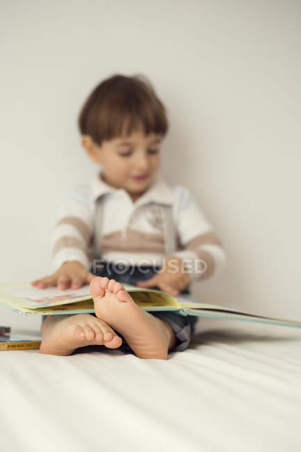 Menino livro de leitura na cama — Fotografia de Stock