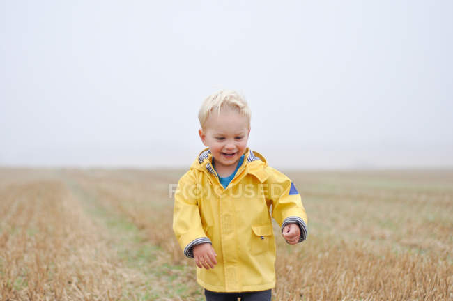 Garçon dans le champ en vêtements de pluie — Photo de stock