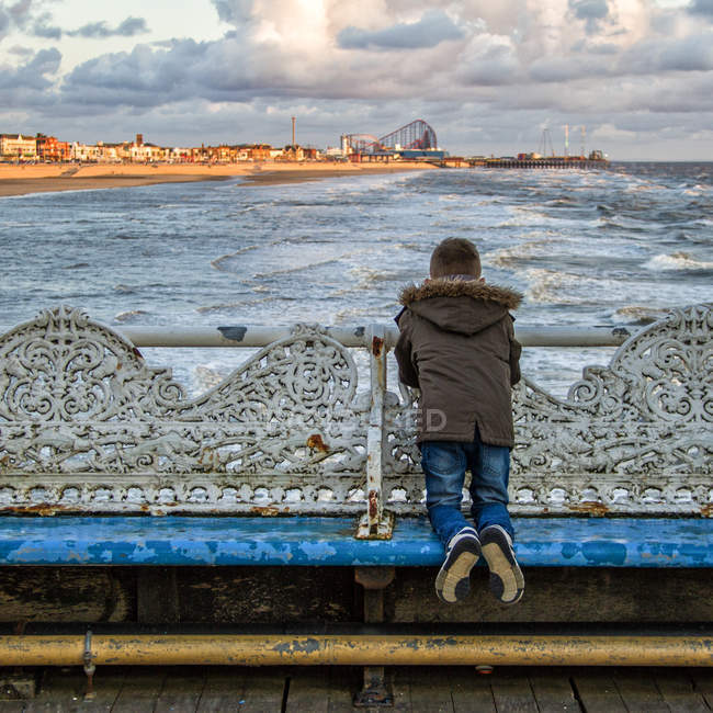 Garçon regardant la plage sur le quai — Photo de stock