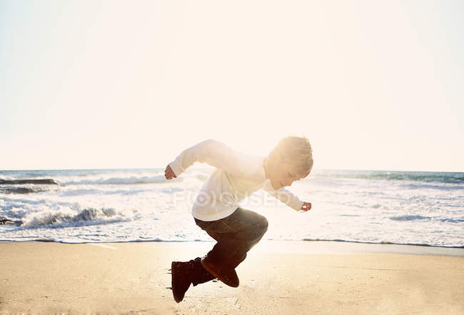 Хлопчик стрибає на пляжі — стокове фото