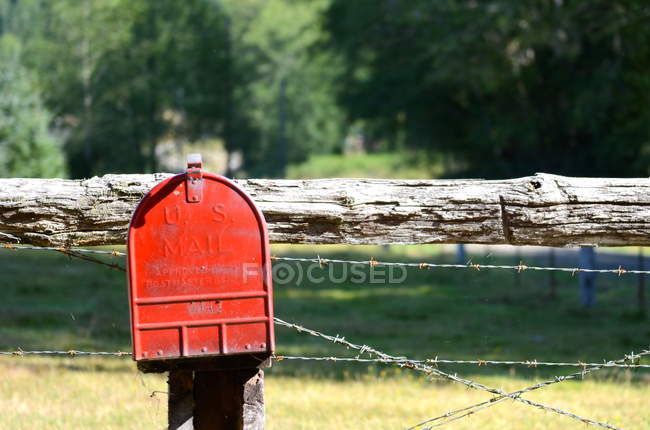 Boîte aux lettres rouge sur poteau de clôture — Photo de stock