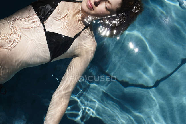Mulher flutua na piscina — Fotografia de Stock