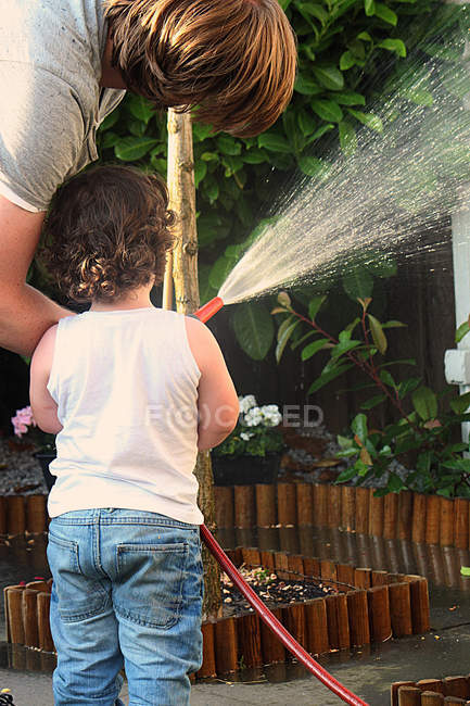 Hombre con niño regando las plantas - foto de stock