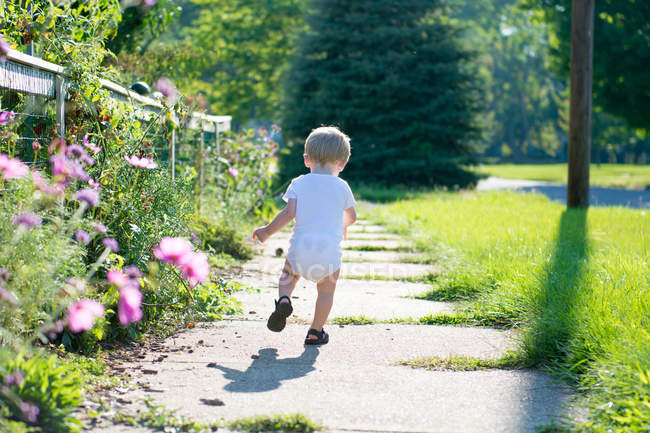 Menino correndo ao longo da calçada — Fotografia de Stock