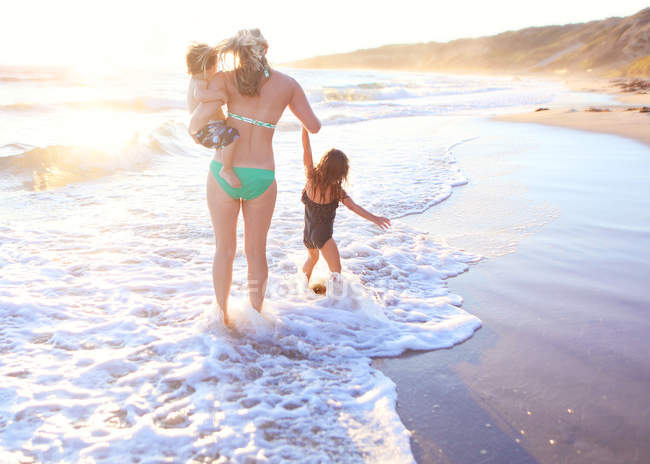 Mãe caminhando ao longo da praia arenosa — Fotografia de Stock