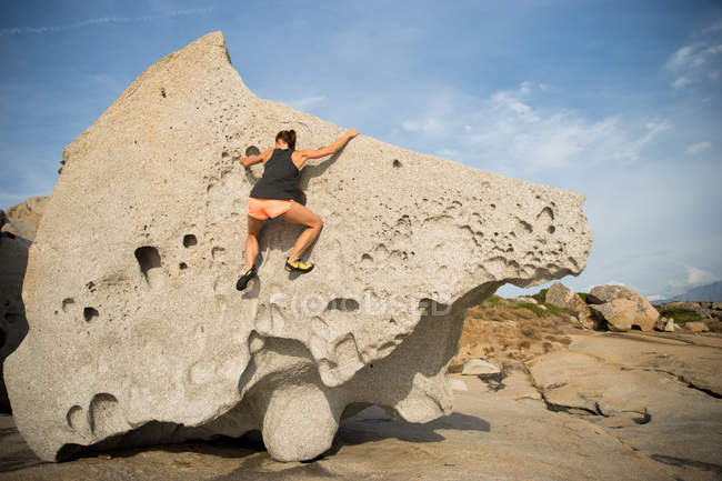 Женщина карабкается по большому камню — стоковое фото