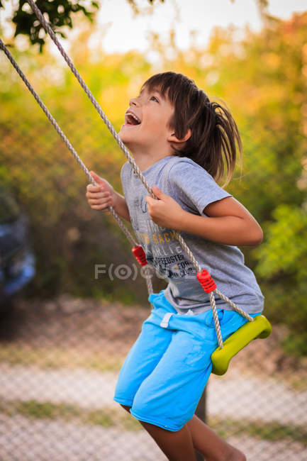 Мальчик смеется и качается на качелях — стоковое фото