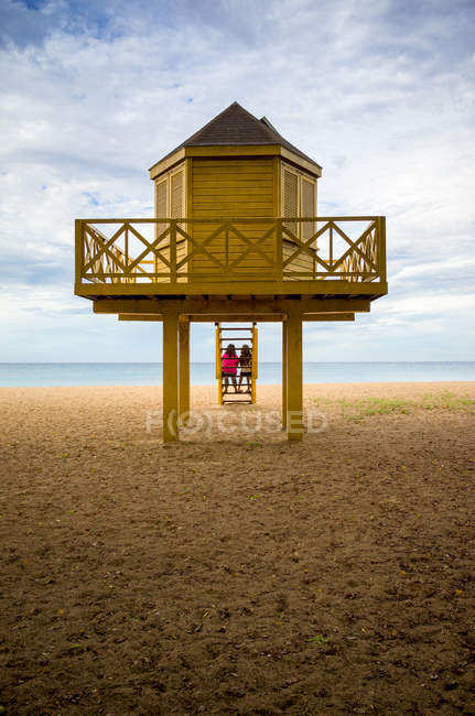 Dos personas sentadas en la playa - foto de stock