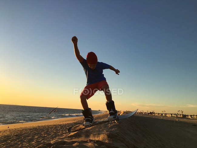 Niño sandboarding en la playa - foto de stock