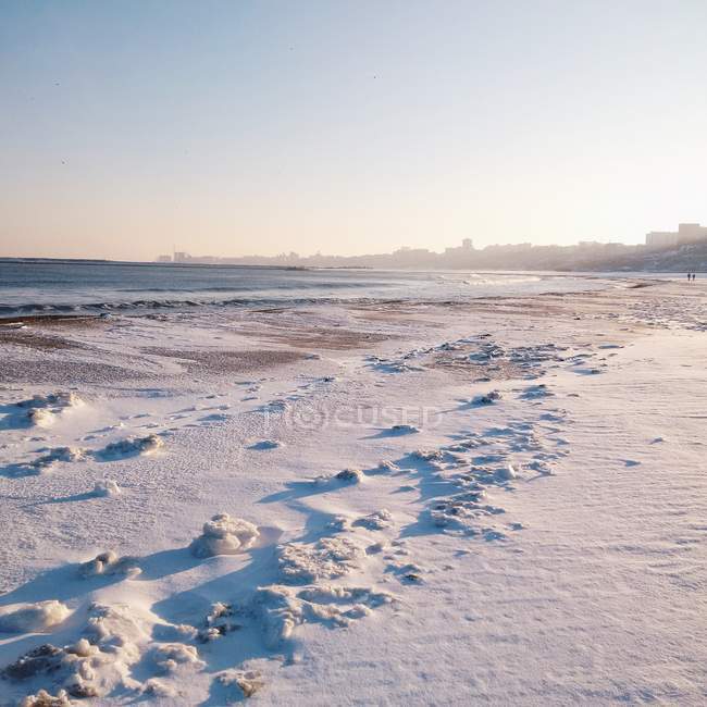 El sol brilla playa cubierta de nieve - foto de stock