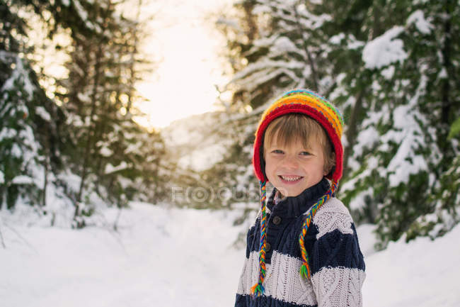 Усміхнений хлопчик стоїть у снігу — стокове фото
