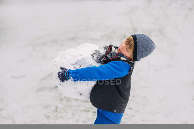 Garçon portant une grosse boule de neige — Photo de stock