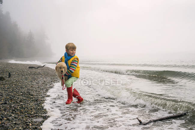 Boy carrying puppy dog — Stock Photo