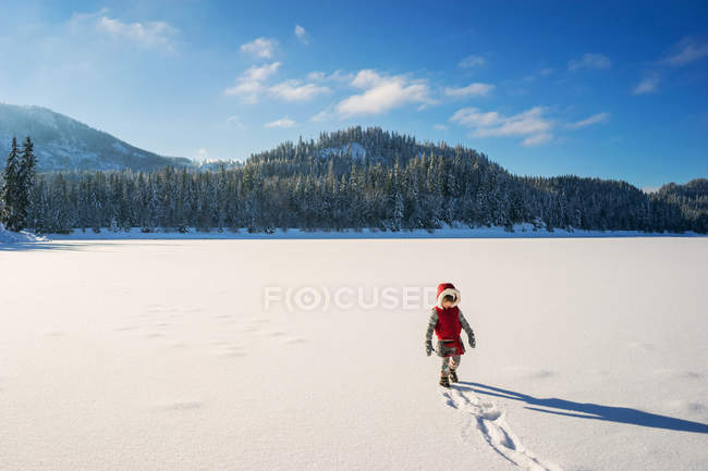 Girl walking on snow covered lake — Stock Photo
