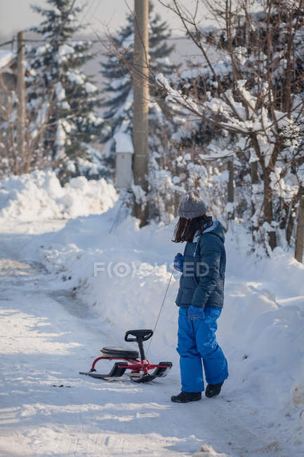 Menina puxando trenó no caminho nevado — Fotografia de Stock