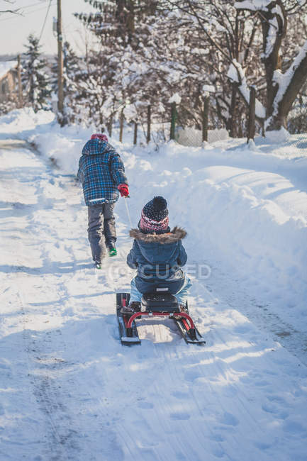 Boy pulling sister on sledge — Stock Photo
