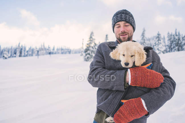 Человек держит золотистого ретривера щенка — стоковое фото