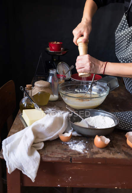 Female hands pour condiment into bowl — Stock Photo