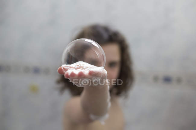 Girl holding soap bubble in hand — Stock Photo