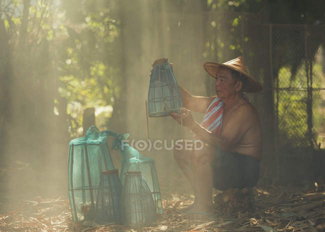 Старший чоловік сидить з рибальськими горщиками — стокове фото