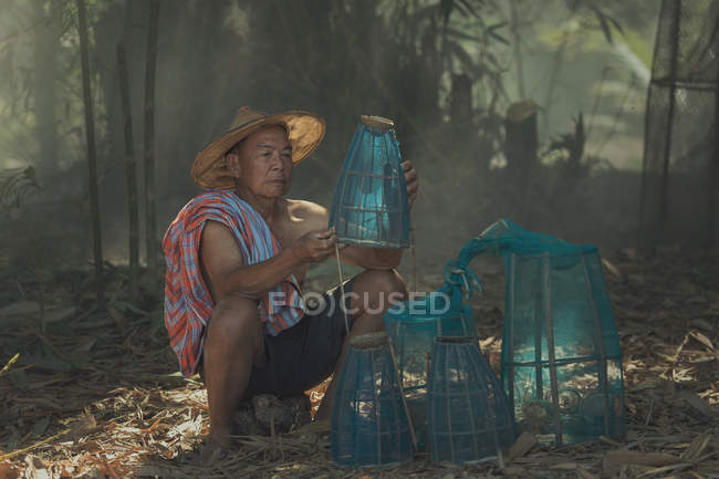 Uomo anziano seduto con pentole da pesca — Foto stock