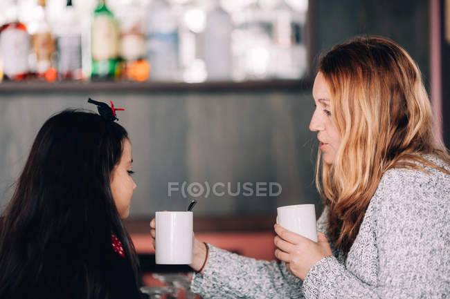 Mujer y chica disfrutando de bebidas calientes - foto de stock