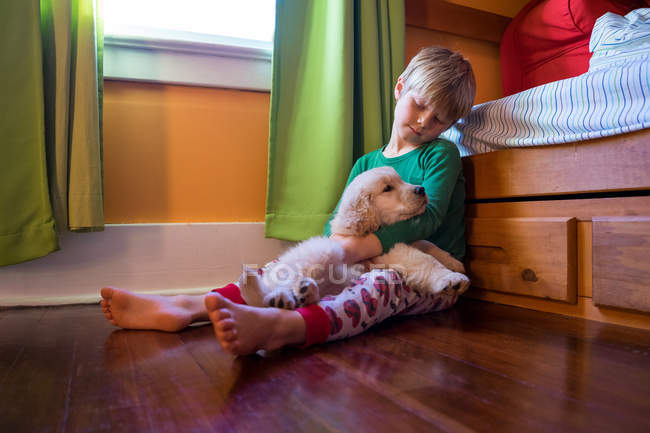 Мальчик сидит на полу с собакой — стоковое фото
