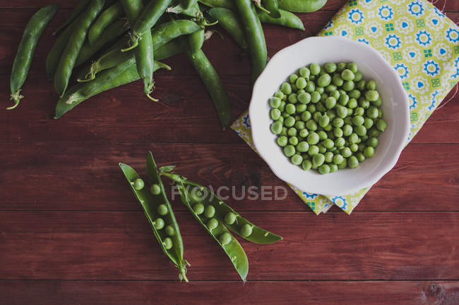 Fresh green peas on wooden table — Stock Photo