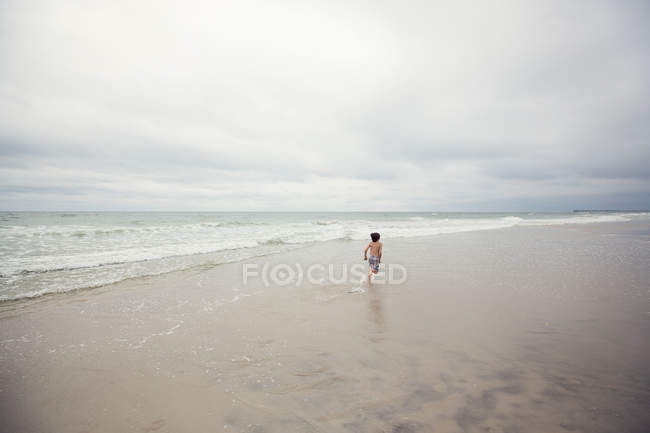 Мальчик убегает вдоль пляжа — стоковое фото