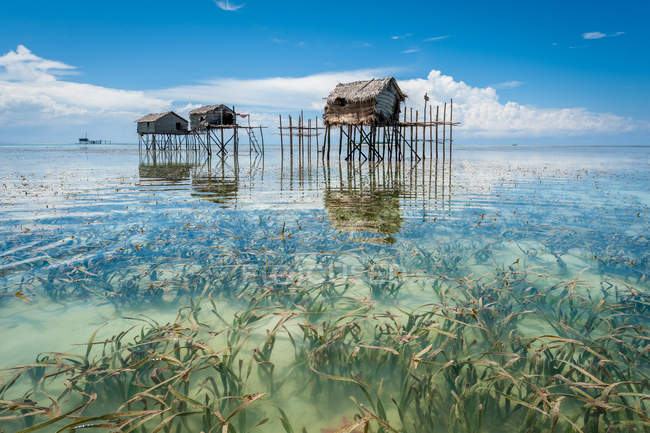 Stelzenhütten spiegeln sich im Meer — Stockfoto