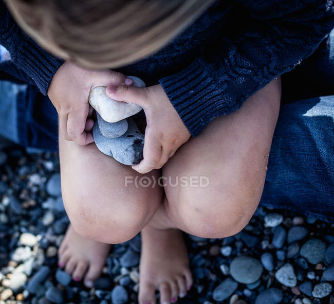 Toddler at the beach collecting pebbles — Stock Photo