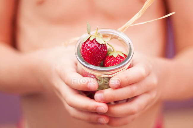 Garçon tenant pot de fraises — Photo de stock