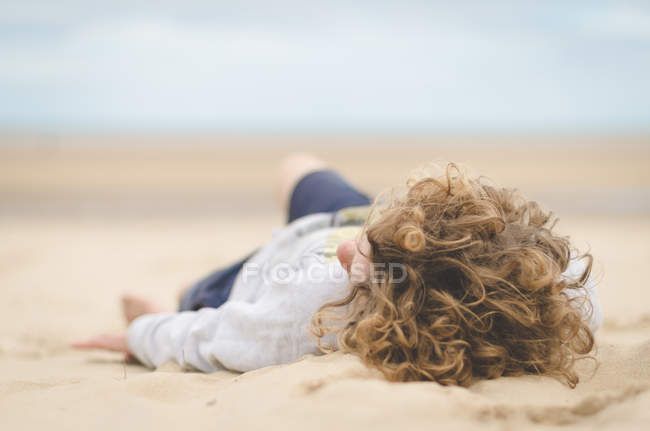 Garçon couché sur la plage — Photo de stock