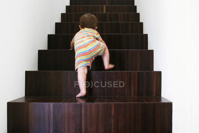 Baby climbing wooden stairs — Stock Photo