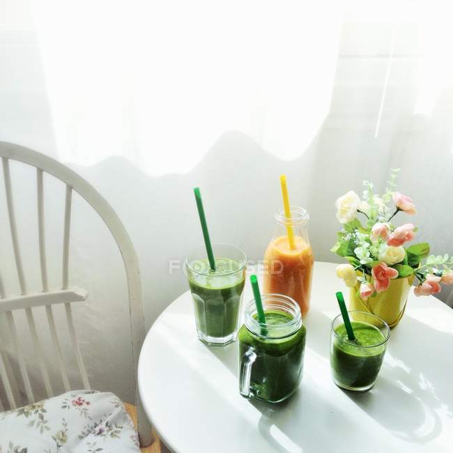Зеленые смузи и морковные коктейли — стоковое фото