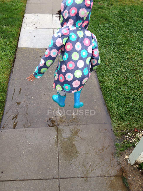Girl jumping into puddle — Stock Photo