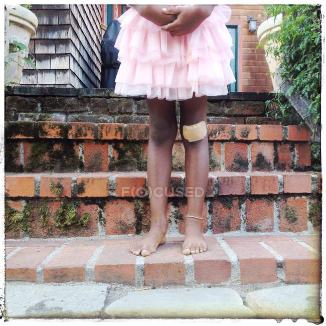Menina com ajuda banda no joelho — Fotografia de Stock