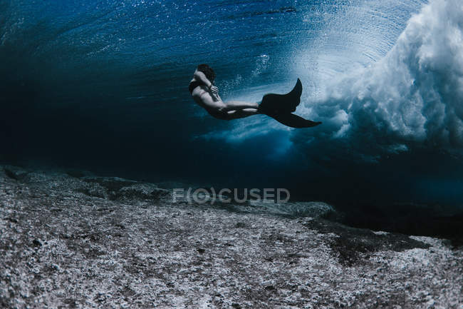 Mujer nadando bajo las olas - foto de stock