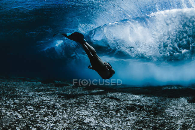 Female swimming under waves — Stock Photo