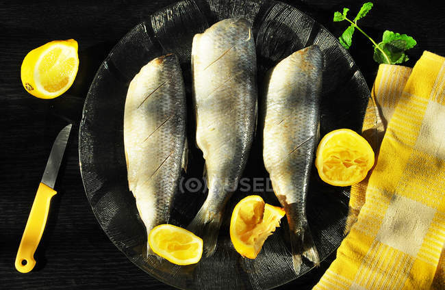 Рыбы на тарелке с лимонами — стоковое фото