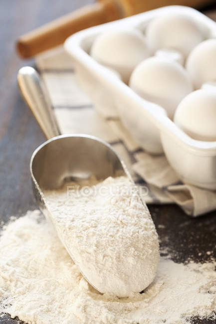 Harina y huevos en la mesa - foto de stock