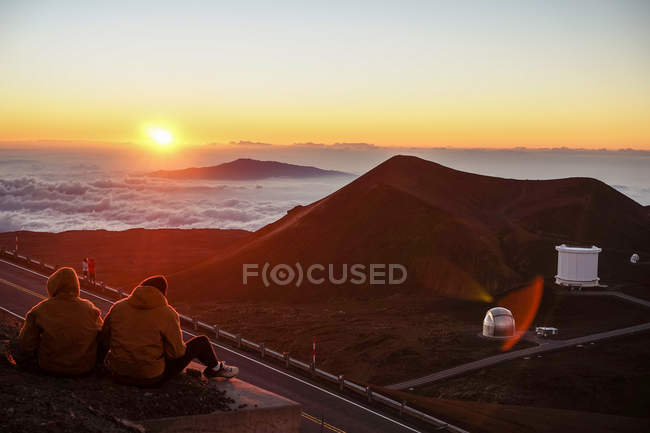 Pareja viendo la puesta de sol en las montañas - foto de stock