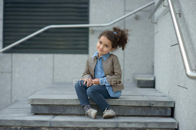 Chica sonriente sentada en los escalones - foto de stock
