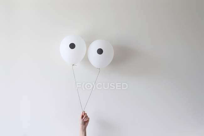 Hand holding pair of balloons — Stock Photo