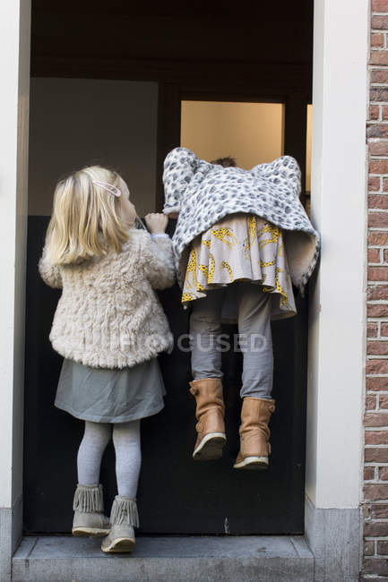 Two girls trying to climb over a door — Stock Photo