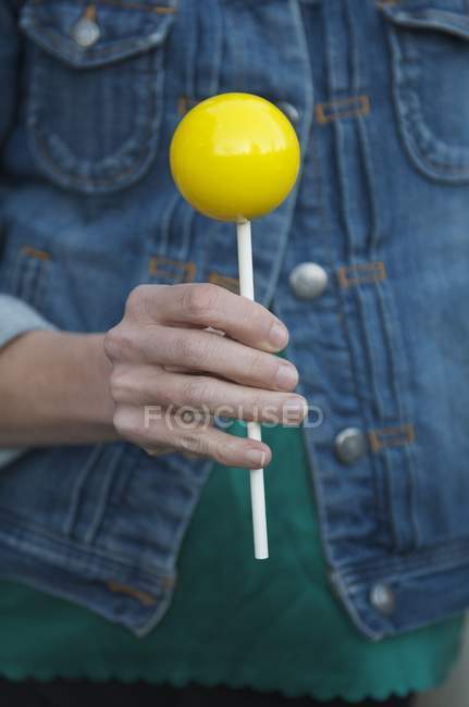 Woman holding yellow lollipop — Stock Photo