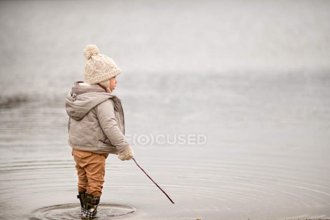 Niño de pie en el lago - foto de stock