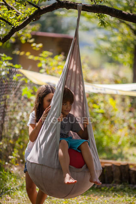 Fille poussant garçon sur swing — Photo de stock