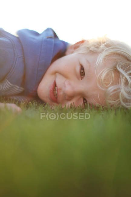 Sonriente chico acostado en la hierba - foto de stock