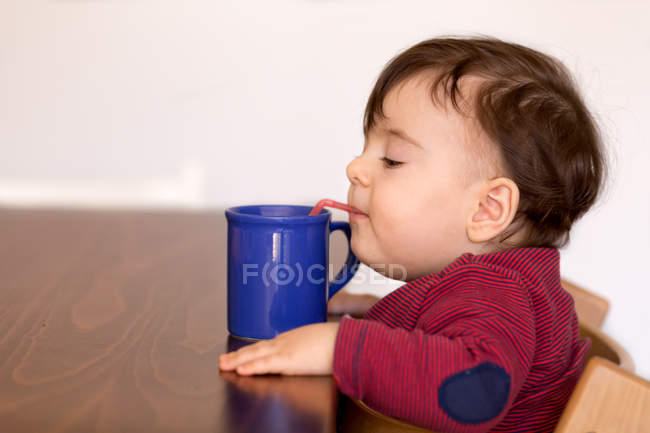 Мальчик пьет воду с соломой — стоковое фото
